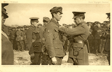 Postcard - sepia, Decorating a Canadian on the Field of Battle, c1917
