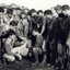 A football team and their coach poss for a photo on a muddy football ground.