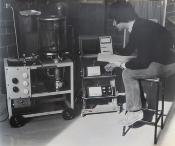Photograph, Student operating vacuum equipment in a metallurgy laboratory, 1974