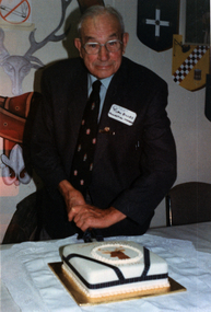 A man sits behind a decorated cake