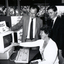 Three people around a computer