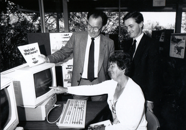 Three people around a computer