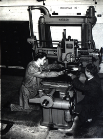 Two men work on a machine