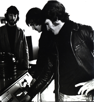 Three men at a machine