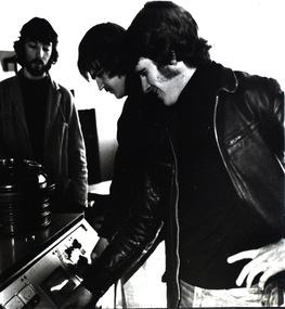Three men at a machine