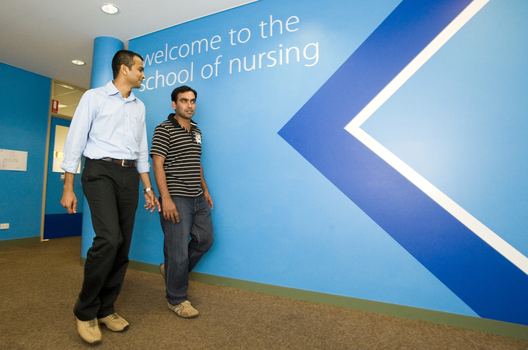 Two men walk in the School of Nursing