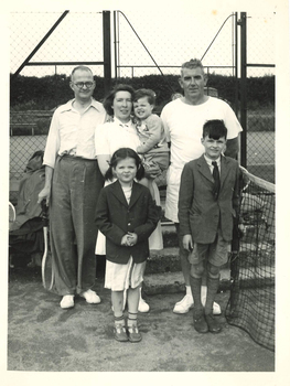 Six people in front of a tennis court