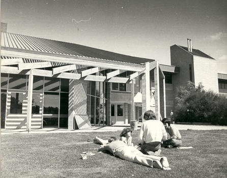 Four people on the grass outside a building