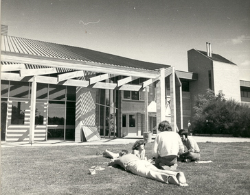 Four people on the grass outside a building