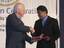 Two men shaking hands and exchanging a gift