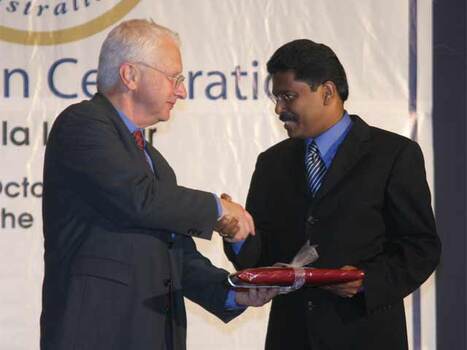 Two men shaking hands and exchanging a gift