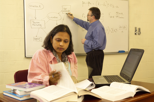 Student studying and lecturer writing on the board