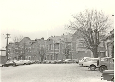 Cars parked on Lydaird Street in front of double storey school