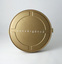 Bronze-gold metal film canister. Small white labels holding lid on.
