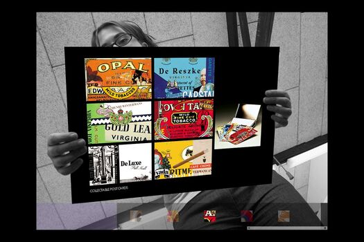 Black and white photograph of student, viewed from below holding a coloured presentation card of their work: a series of collectable postcards.