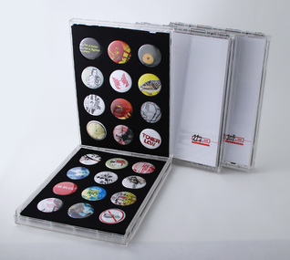 Three cases of a limited edition run of 240 packs, each containing 24 badges. Case #221 of 240 is open to display badges.