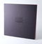 Square format publication, black textured card cover with black debossed text.