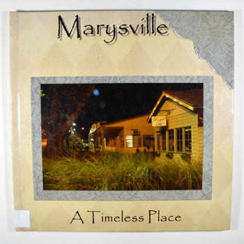 Hardcover. Front cover has a photograph of the Corner Cupboard Cafe in Marysville taken at night. In the foreground are some grasses and to the left of the shop is a large oak tree. 