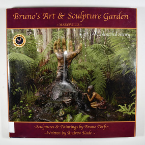 Hardback. Front cover has a photograph of a sculpture of a large hand with a waterfall flowing from it. To the right of the hand there is a sculpture of a girl kneeling by the waterfall capturing water in her hands. The sculptures are surrounded by the forest. The back cover has a photograph of a sculpture of two figures holding hands, one of whom is carrying a water jug, surrounded by the forest.