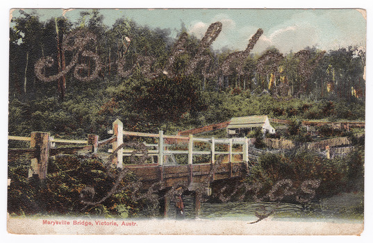 Shows a wooden, white painted bridge that crosses over a river. In the foreground, standing on the bank of the river, is a young girl wearing a hat. In the background is a timber building surrounded by wooden fences.  Birthday Greetings have been written in glitter across the image. On the reverse of the postcard is a message and an address handwritten in black ink. It appears to have had a postage stamp affixed but that has been removed.