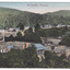 Shows the early Marysville township in Victoria. It shows various wooden buildings some of which are surrounded by wooden fences. In the background are forested mountains. The sky is tinted blue at the top and pink towards the hills. On the reverse of the postcard is space to write a message and an address and to place a stamp. The postcard is unused.