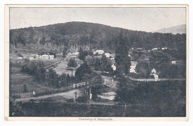 Shows Marysville in it's early days. There a a few buildings, some fencing and in the foreground is a bridge over a river. In the background is a heavily forested mountain. The photograph appears to have been taken from a high position; possibly near where the Anglican Church now stands. On the reverse there is a message and an address handwritten in black ink. There is also an orange one penny Victorian postage stamp and two date stamps in black ink.