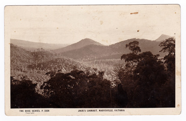 An early sepia photograph of the view of the surrounding mountains taken from Jock's Lookout which is on the Marysville-Wood's Point Road near Marysville in Victoria. Shows heavily forested mountains in the background. On the reverse of the postcard is a space to write a message and an address and to place a postage stamp. The postcard is unused.