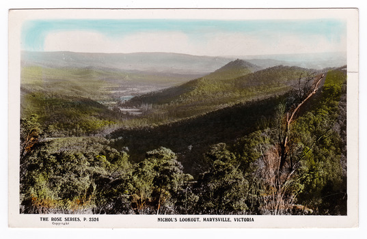 Shows the view of the surrounding hills from Nichol's Lookout which is on the Marysville-Wood's Point road near Marysville in Victoria. In the background are a series of heavily forested mountains. On the reverse is a handwritten message.