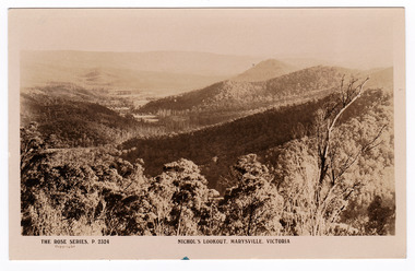 Shows view of the surrounding hills from Nichol's Lookout which is on the Marysville-Wood's Point road near Marysville in Victoria. In the background are a series of heavily forested mountains. On the reverse is a handwritten message.
