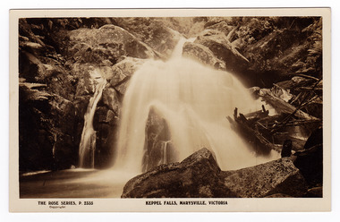 Shows Keppel Falls near Marysville in Victoria. Shows the falls cascading down over some large boulders into a pool of water. There are also a number of fallen logs at the right of the falls. On the reverse of the postcard is a space to write a message and an address and to place a postage stamp. The postcard is unused.