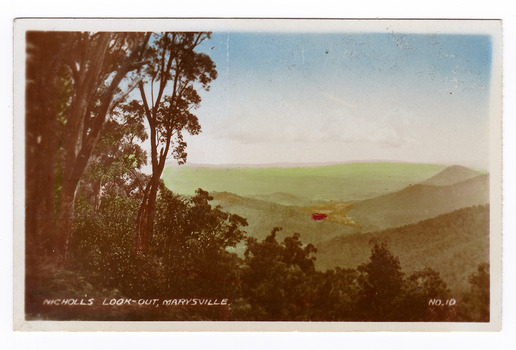 Shows the view from Nicholl's Look-out near Marysville in Victoria. Shows a view of mountains with trees in the foreground. The title of the photograph is handwritten in white ink on the lower edge.