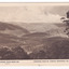 Shows the view from Mount Gordon over the mountains surrounding Marysville in Victoria. In the foreground are some trees. In the background can be seen a series of heavily forested mountains. On the reverse of the postcard is a space to write a message and an address and to place a postage stamp. The postcard is unused.