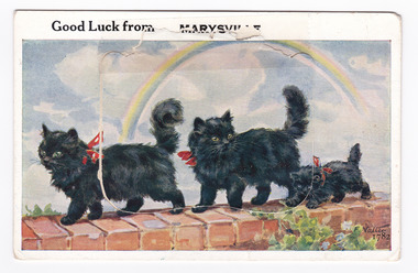 Shows an illustration of a line of two black cats and a black kitten walking along the top surface of a brick wall. All three cats have red bows around their necks. The title of the postcard is written along the top edge. There is a lift-up flap in the middle with a pull-out strip of 9 miniature photographs of places of interest in and around Marysville. On the reverse of the postcard is a hand-written message.