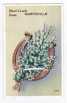 Shows an illustration of a bouquet of white flowers resting on an up-turned horse shoe. The title of the postcard is across the top edge of the postcard. There is a lift-up flap in the middle with a pull-out strip of 9 miniature photographs of places of interest in and around Marysville. On the reverse of the postcard is a space to write a message and an address. There is also a space to place a postage stamp. The postcard is unused.