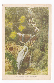Shows Steavenson Falls in Marysville in Victoria. Shows the falls cascading down the mountain surrounded by a forest. On the reverse of the postcard is a space to write a message and an address and to place a postage stamp. The postcard is unused.