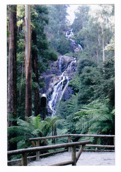 Shows Steavenson Falls in Marysville in Victoria. Show the falls cascading down the mountain over large rocks. In the foreground can be seen the viewing platform.