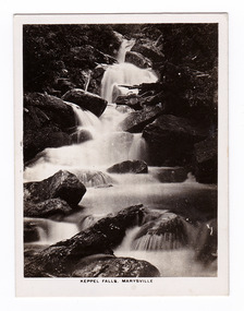 Shows Keppel Falls which is accesible from Lady Talbot Drive. Shows the falls cascading over large rocks through the forest. The title of the photograph is along the lower edge of the photograph.