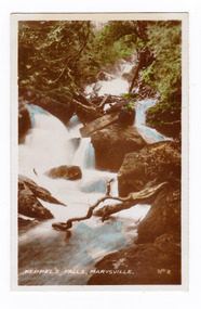 Shows Keppel Falls near Marysville in Victoria. Shows the falls cascading down over large rocks surrounded by forest. The title of the photograph is written in white ink along the lower edge.