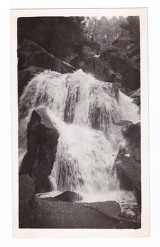 Shows Keppel Falls near Marysville in Victoria. Shows the falls cascasding down over large rocks surrounded by the forest.