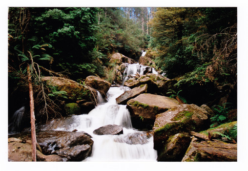 Shows Keppel Falls near Marysville in Victoria. Shows the falls cascading down over large rocks through the forest.