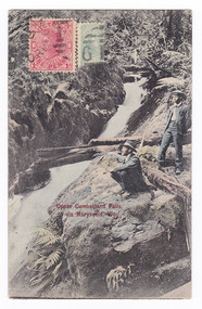 Shows two men, one sitting and one standing, at the edge of the waterfall which is cascading down the mountain. There are a few fallen logs lying across the falls and the falls are surrounded by forest. On the front of the postcard are two postage stamps. One is an orange one  penny Victorian stamp and the other is green. There is also a date stamp in black ink. On the reverse of the postcard is an address in black ink as well as the sender's name.