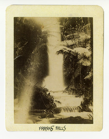 Shows the falls cascading down the mountain into a pool at the bottom. The falls are surrounded by tree ferns. The title of the photograph is along the lower edge in black ink. On the reverse of the photograph is a stamp from the Armstrong Collection at 42 Station Street in Sandringham in Victoria.