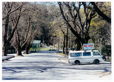Show Murchison Street in Marysville in Victoria. Shows the view looking up the street towards the Marysville-Buxton Road with the Christ Church in the background. In the foreground in the right of the photograph is a white van with a sign for the Cross Country Ski Hire shop attached to the roof.