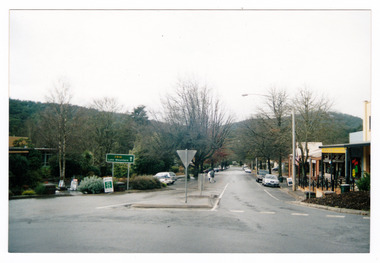 Shows Murchison Street in Marysville in Victoria. Shows the view looking up Murchison Street from the corner with Lyell Street. There are buildings and cars parked on both sides of the street. In the foreground is the sign to Lake Mountain. The photograph appears to have been taken after rain.