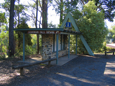 Shows the tourist information booth at the entrance to Marysville, in Victoria, on Murchison Street. Shows also a brown tourist sign guiding visitors to Steavenson Falls.