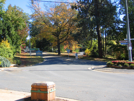 Shows the corner of Murchison and Lyell Streets in Marysville in Victoria. In the right of the photograph is a roundabout with signage leading to various destinations. In the left of the photograph is a wooden sign that informs visitors of the location of various accommodation choices. There is also a green sign directing visitors as to the direction to take to to Melbourne.