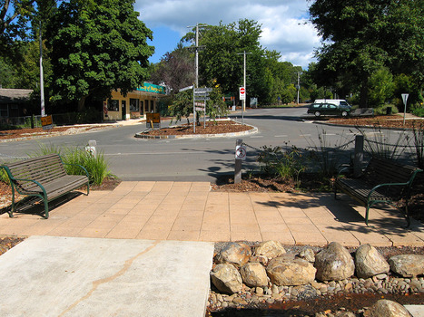 Shows the view looking up Pack Road from Murchison Street in Marysville in Victoria. Shows a signpost that with various destinations and distances in an around the local area. In the background can be seen some local shops with cars parked on the opposite side of the street.