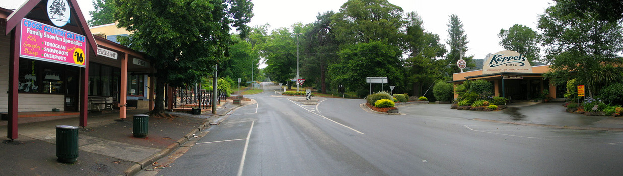 Shows Murchison Street in Marysville in Victoria. The view is looking up Murchison Street to the corner roundabout at Lyell Street. In the left of the photograph is the Cross Country Ski Hire with more buildings leading up the street. In the right of the photograph is the Keppels Hotel.