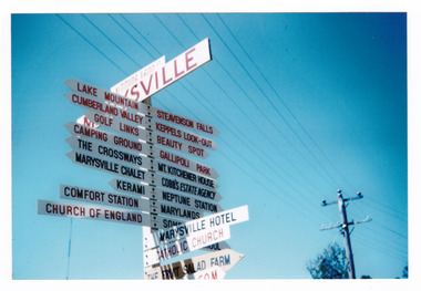 Shows the signpost at Signpost Corner in Marysville in Victoria. Shows various tourist and places of interest sites in and around Marysville and the district.