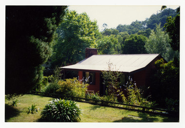 Shows a small house that is roofed in corrugated iron. This house was situated on the corner of Pack and Falls Roads in Marysville in Victoria.